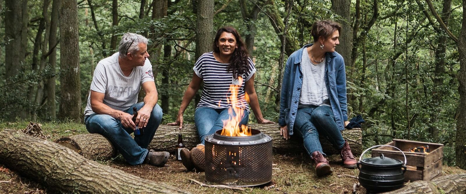 Adults relaxing around a campfire in the woodland at Drovers Rest