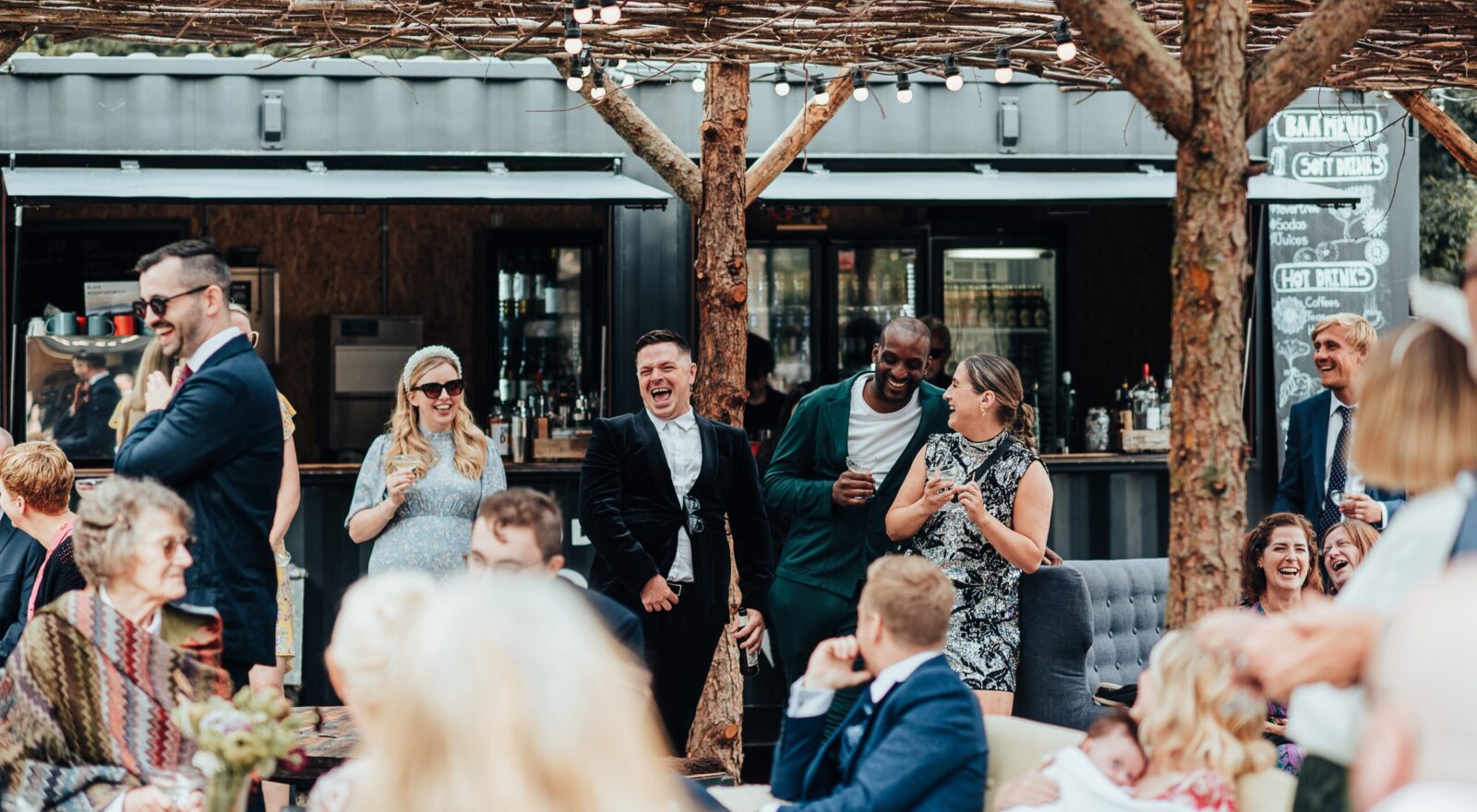 Guests laughing and enjoying drinks by the bar in the Drovers Rest courtyard