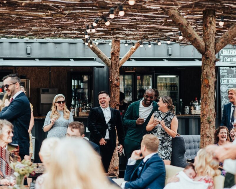 Guests laughing and enjoying drinks by the bar in the Drovers Rest courtyard